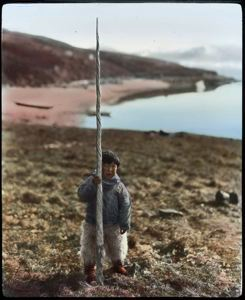 Image of Narwhal tooth held upright by young boy 